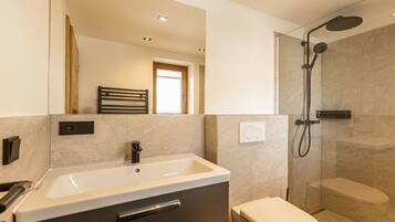 A modern bathroom with a sink, toilet, and shower.