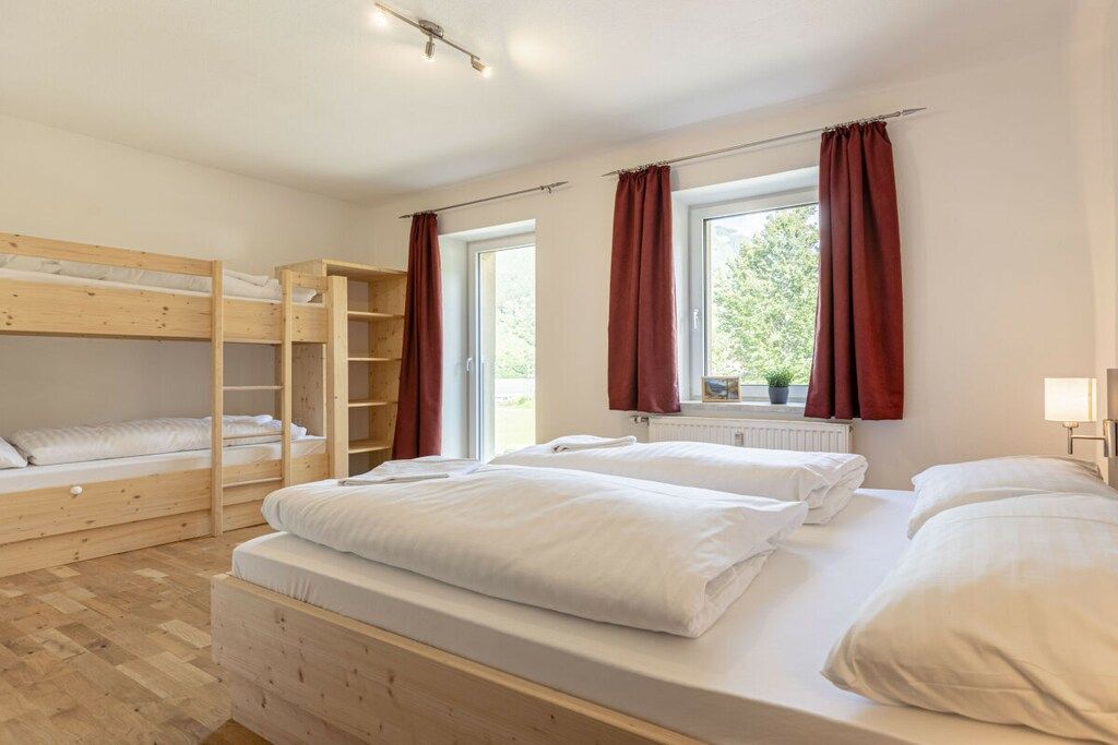 A room with bunk beds, a window with curtains, and a radiator.