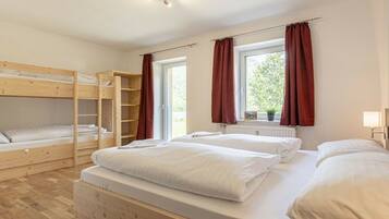 A room with bunk beds, a window with curtains, and a radiator.