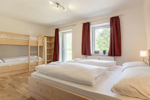 A room with bunk beds, a window with curtains, and a radiator.
