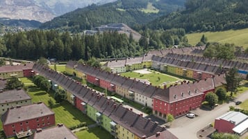 A residential area with multiple two-story buildings, a central courtyard, and a mountainous backdrop.