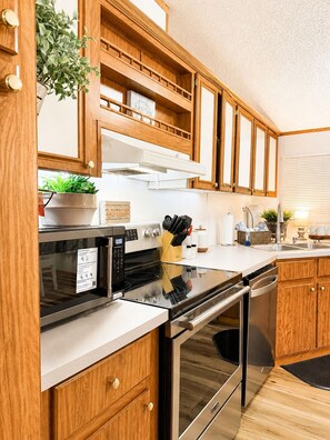 Een moderne keuken met houten kastjes, roestvrijstalen apparatuur en een inbouwoven.