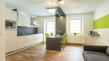 A modern kitchen with white cabinets, a central island, and a dining area with chairs.