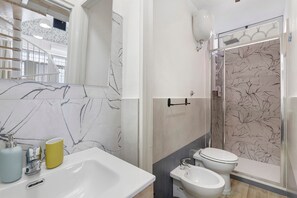 A bathroom with a marble backsplash, a sink, a toilet, a bidet, and a shower with a glass door. - Apartment 'Chicco & Mirca Loft in Rome Metro A' with Wi-Fi and Air Conditioning (Roma)