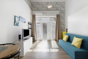 A modern living room with a television, a sofa, and a dining area. - Apartment 'Chicco & Mirca Loft in Rome Metro A' with Wi-Fi and Air Conditioning (Roma)