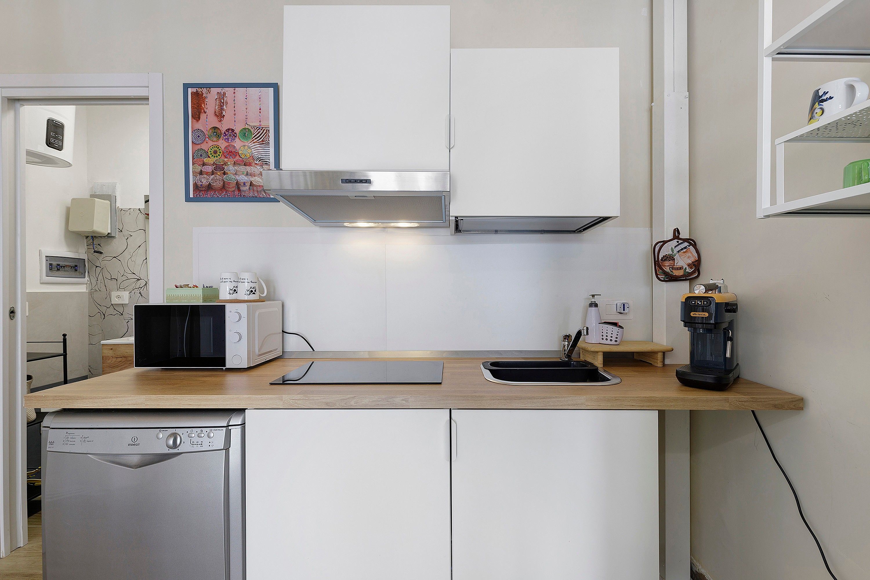A compact kitchen with a microwave, toaster, coffee maker, and a dishwasher.