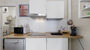 Cozinha compacta equipada com micro-ondas, torradeira, máquina de café e lava-louças.