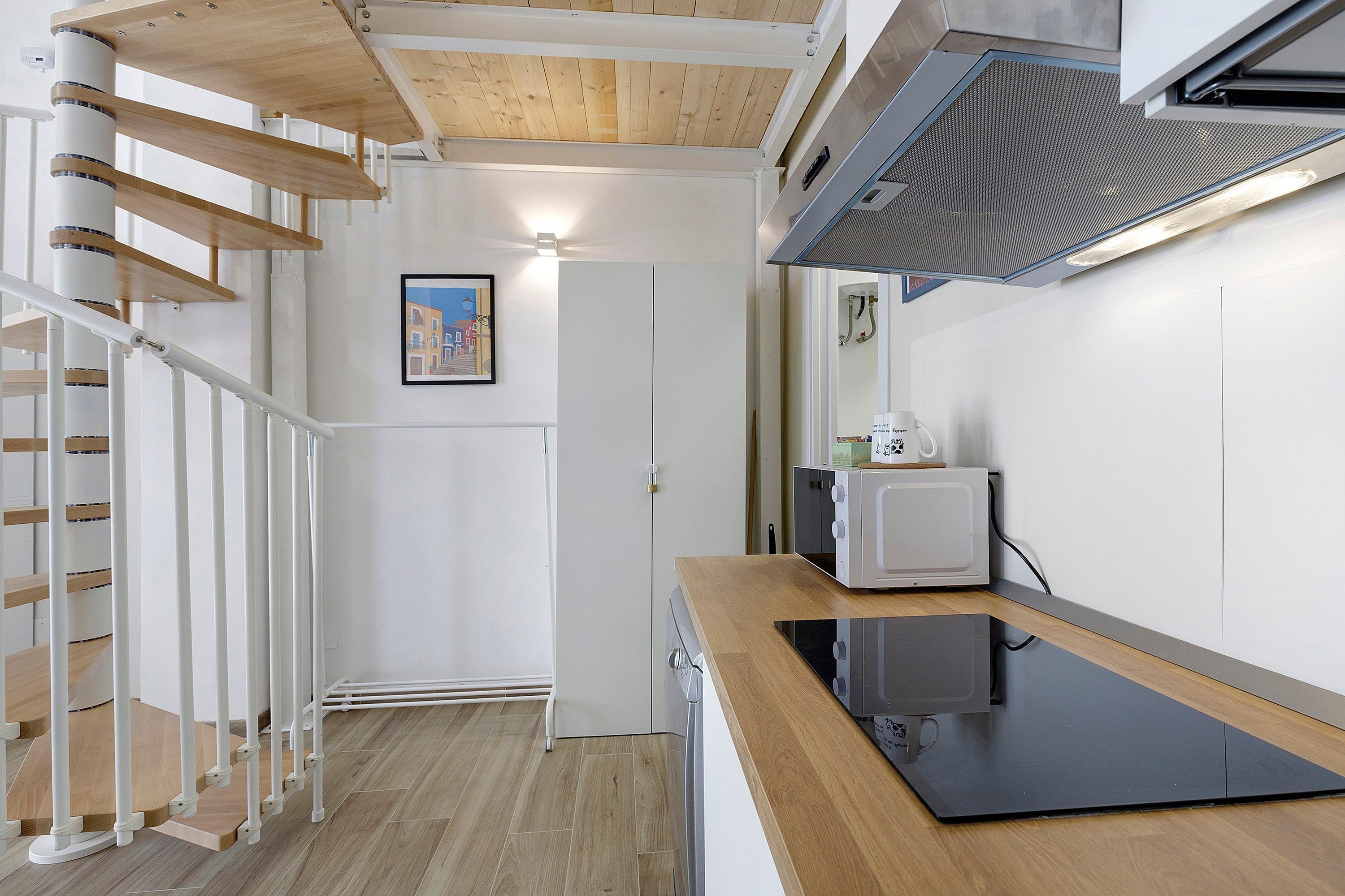 A modern kitchen with a wooden countertop, a microwave, and a stove.