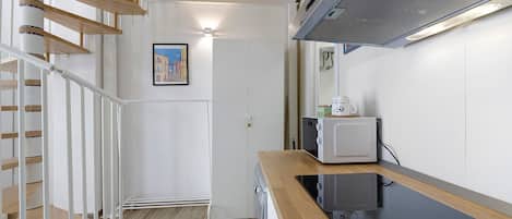 A modern kitchen with a wooden countertop, a microwave, and a stove.
