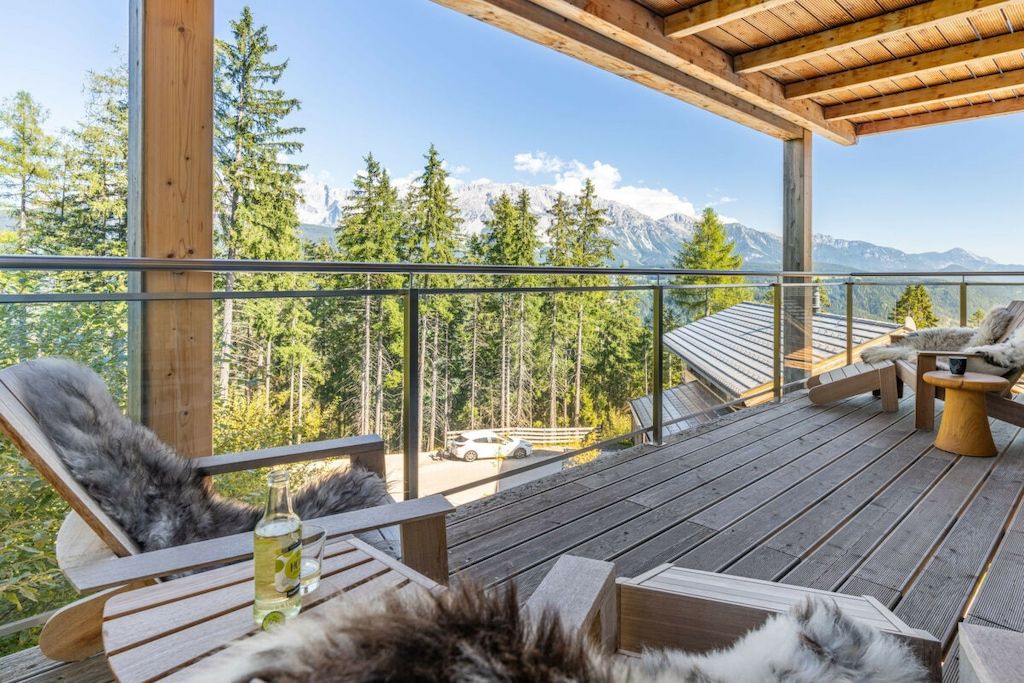 A wooden deck with outdoor seating, overlooking a mountainous landscape.
