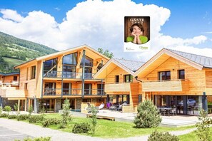 A modern wooden building with multiple levels, large windows, and outdoor seating areas. - Apartment with 1 bedroom (St. Georgen am Kreischberg)