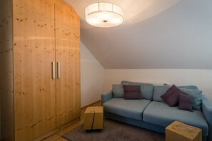 Ein Zimmer mit einem Holzschrank, einem hellblauen Sofa und einem kleinen Holzschemel.