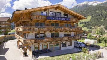 A multi-story wooden building with balconies, labeled 'ALPS RESORTS,' surrounded by a mountainous landscape.