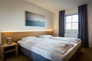 A hotel room with a large bed, bedside lamps, a painting on the wall, and a window with curtains. - Holiday apartment # 8 with balcony (Turrach)