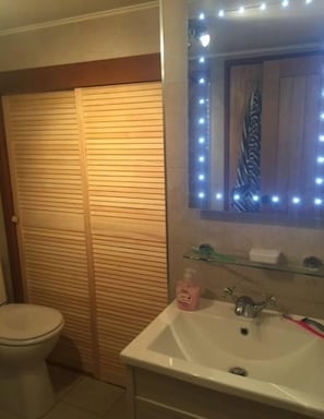Een badkamer met toilet, wastafel en spiegel met verlichting.