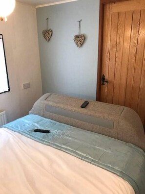 Een slaapkamer met een bed, een houten deur en twee decoratieve hartjes aan de muur.