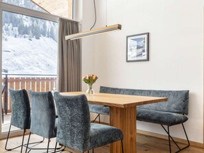 A modern dining area with a wooden table, grey upholstered chairs, a bench, a vase with flowers, a pendant light, and a framed picture on the wall. - Apartment in Rauris With Swimming Pool (Rauris)
