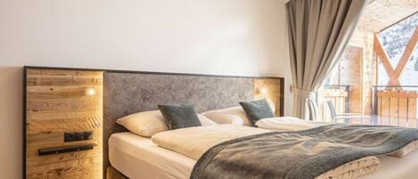 A bedroom with a wooden headboard, a bed with white bedding, and a view of a wooden deck outside.