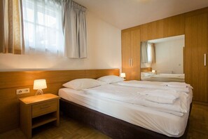 Ein Hotelzimmer mit einem großen Bett, einem Nachttisch mit Lampe, einem Kleiderschrank und einem Spiegel.