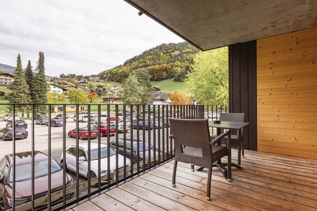 Un balcon donnant sur un parking et un paysage vallonné.