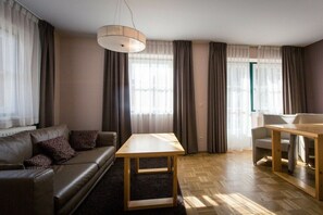 A modern living room with a leather sofa, a wooden coffee table, and a dining area with a table and chairs. - Holiday apartment # 6 with balcony (Turrach)
