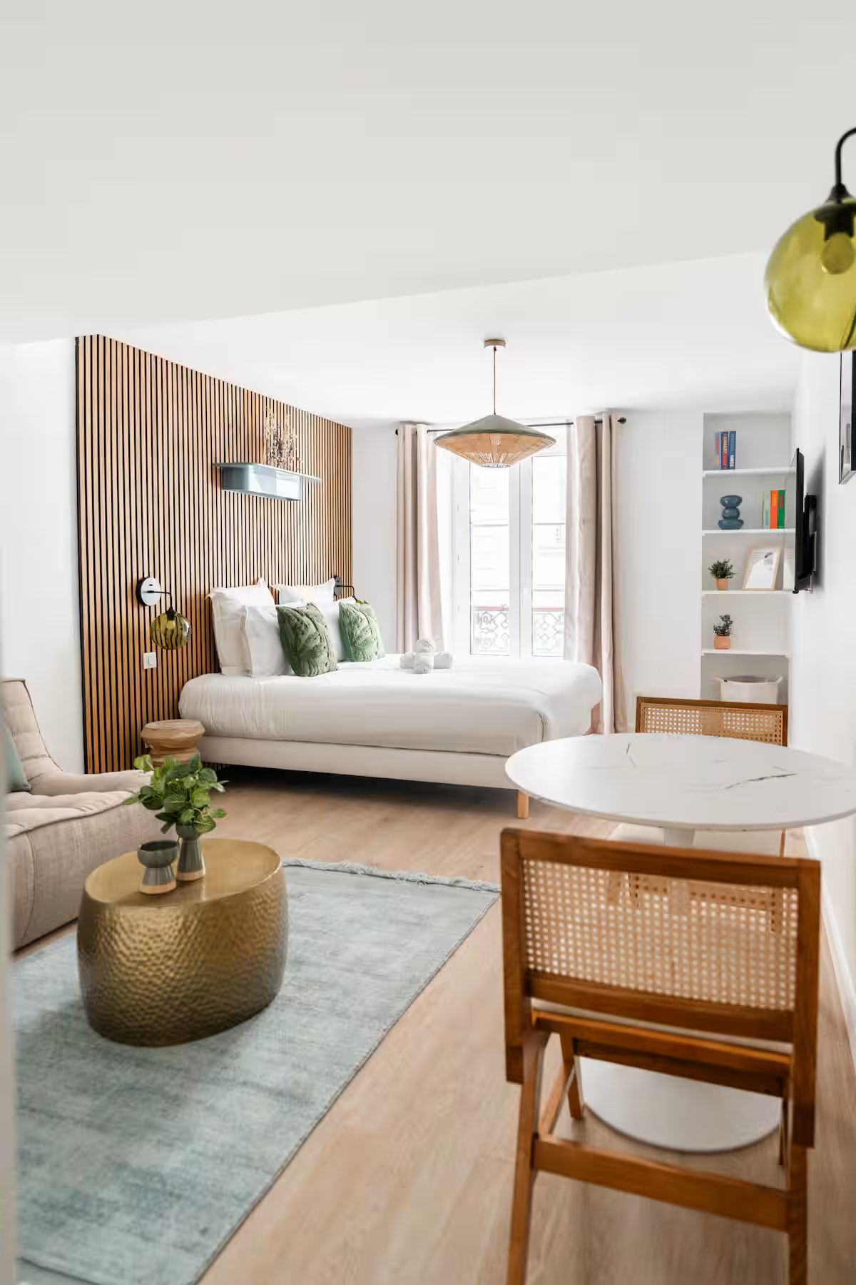 A modern living room with a sofa, a round dining table, and a large window.