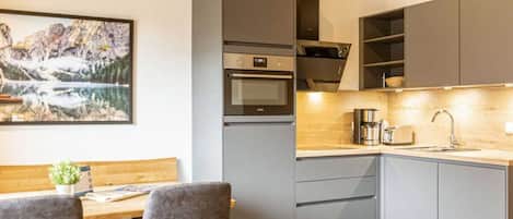 A modern kitchen with grey cabinets, a built-in oven, and a wooden countertop.