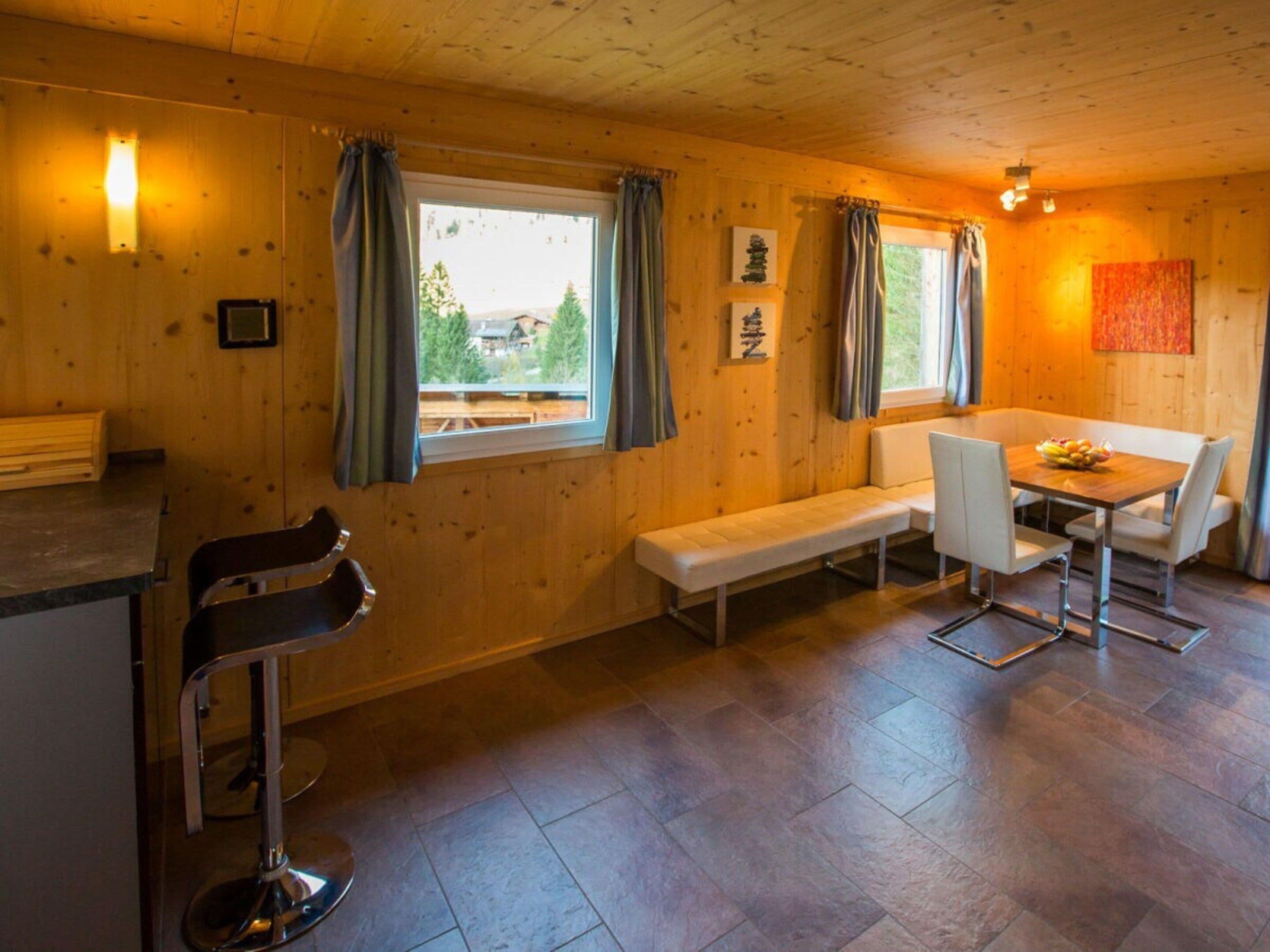 A wooden interior with a bench, table, and bar stool.