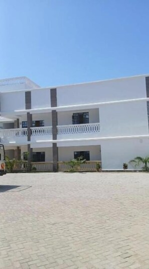 A multi-story building with a flat roof, balconies, and a paved courtyard. - Modern one bedroom along the shores of Diani (Kwale County)
