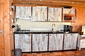 A kitchen with wooden cabinets, a microwave, and a sink. - Holiday home in Limmen with swimming pool (Limmen)