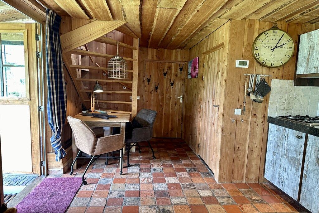 Un intérieur rustique avec des éléments en bois, notamment un bureau, une chaise et une horloge au mur.