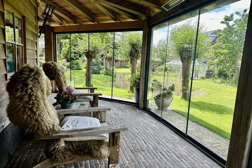 Un espace extérieur aménagé, abrité et doté de sièges, offrant une vue sur un jardin bien entretenu.
