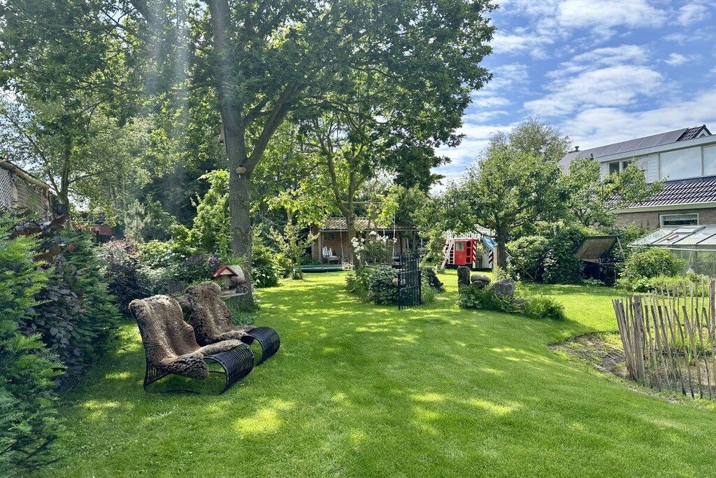 Un jardin bien entretenu, avec une pelouse, une clôture en bois et un véhicule rouge.