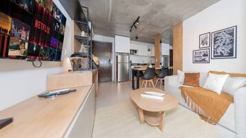 A modern living space with a kitchen, dining area, and a seating area with a sofa and a coffee table.