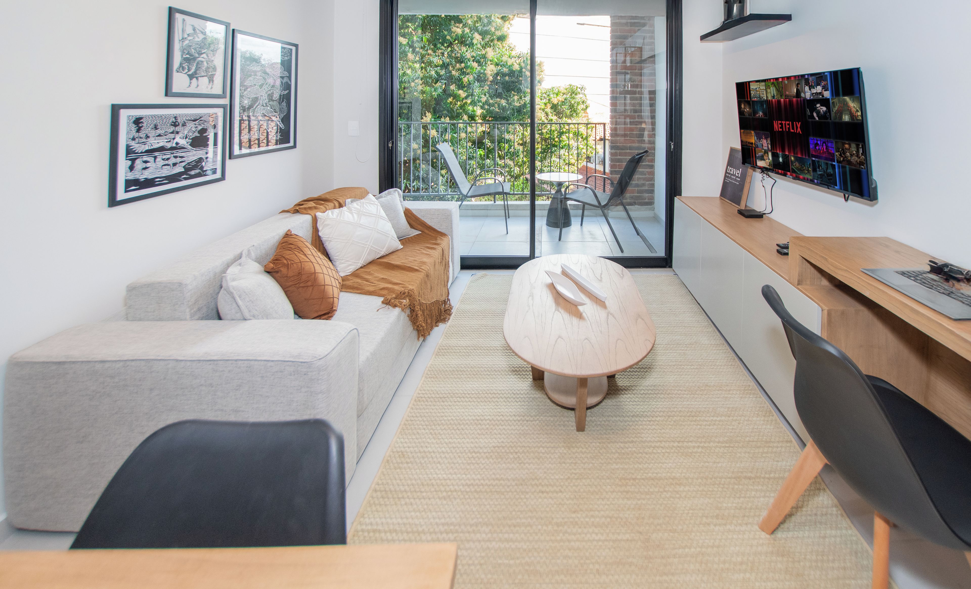 A modern living room with a sofa, a coffee table, and a dining area with a wooden table and chairs.