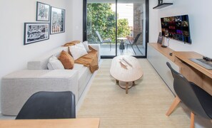 A modern living room with a sofa, a coffee table, and a dining area with a wooden table and chairs. - Corporate Stays First del Sol - 107 (Asunción)