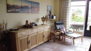 A room with a wooden cabinet, a chair, a small table, and a window with a view of greenery. - Holiday home with 3 bedrooms (Medemblik)