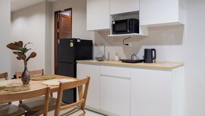 A compact kitchen with a refrigerator, microwave, and a kettle on the counter. - The One Sky  (Rawai)