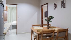 A dining area with a wooden table, chairs, and a vase with a plant. - The One Sky  (Rawai)