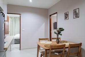 A dining area with a wooden table, chairs, and a vase with a plant. - The One Sky  (Rawai)