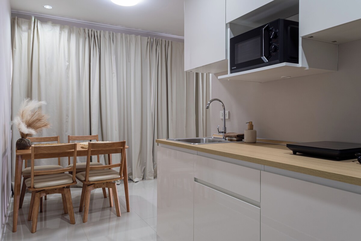A modern kitchen with a built-in microwave, a sink, and a dining area with wooden chairs and a table.