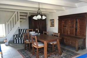 Ein Essbereich mit einem Holztisch, Stühlen, einer Kandelaber, einer Treppe und einem großen Holzschrank.