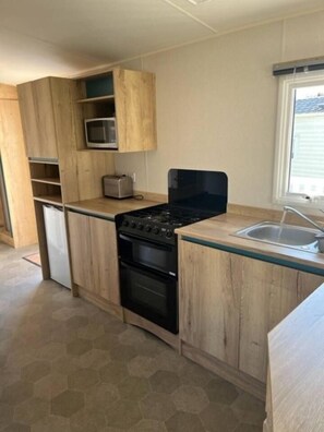 A compact kitchen with a stove, microwave, and toaster. - 97 Nautical Cove – Family Escape | Sleeps 8 (Somerset)