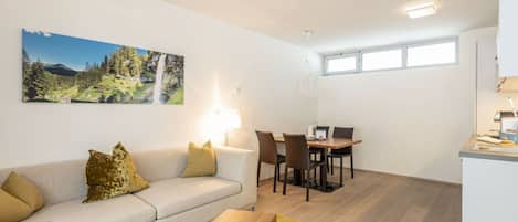 A modern living room with a sofa, coffee table, and dining area.
