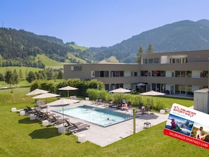 A hotel with a swimming pool, outdoor seating, and a view of the mountains. - Apartment in Radstadt With Swimming Pool (Radstadt)