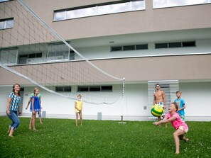 A group of people playing volleyball in a grassy area with a building in the background. - Apartment in Radstadt With Swimming Pool (Radstadt)