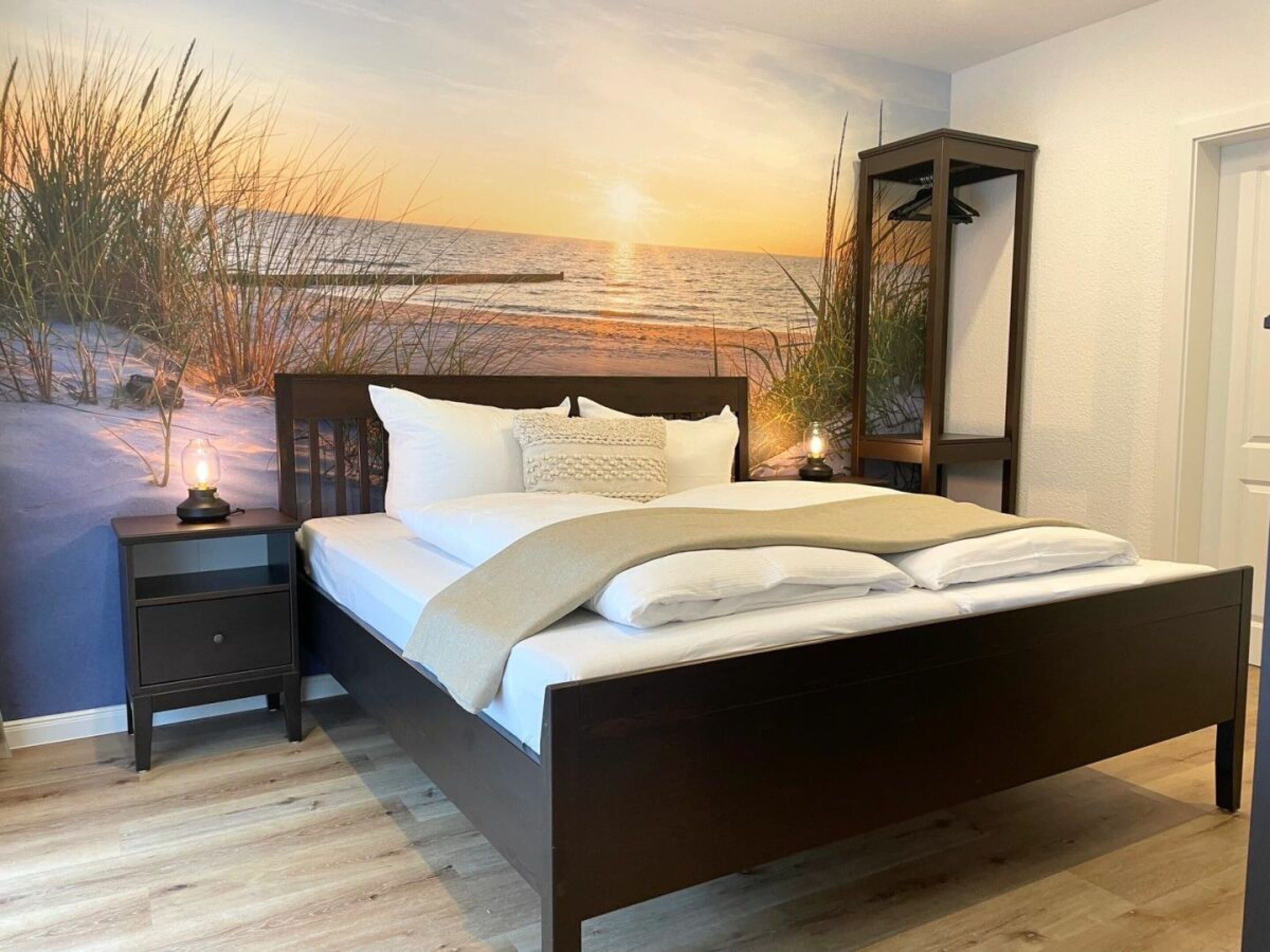 Una camera da letto con un letto, un comodino e un affresco raffigurante una spiaggia.