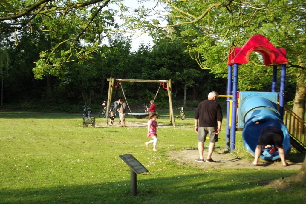 Ein Spielplatz mit Schaukeln, einer Rutsche und einer Bank.