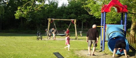 Ein Spielplatz mit Schaukeln, einer Rutsche und einer Bank.