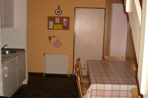 A compact kitchen with a sink, a white door, and a table with a checkered tablecloth. - Holiday home with 2 bedrooms (Bruinisse)